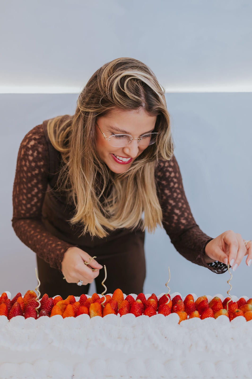 Jéssica Lauar, fundadora do Meu Petit Patisserie, finalizando um bolo de morango com chantilly