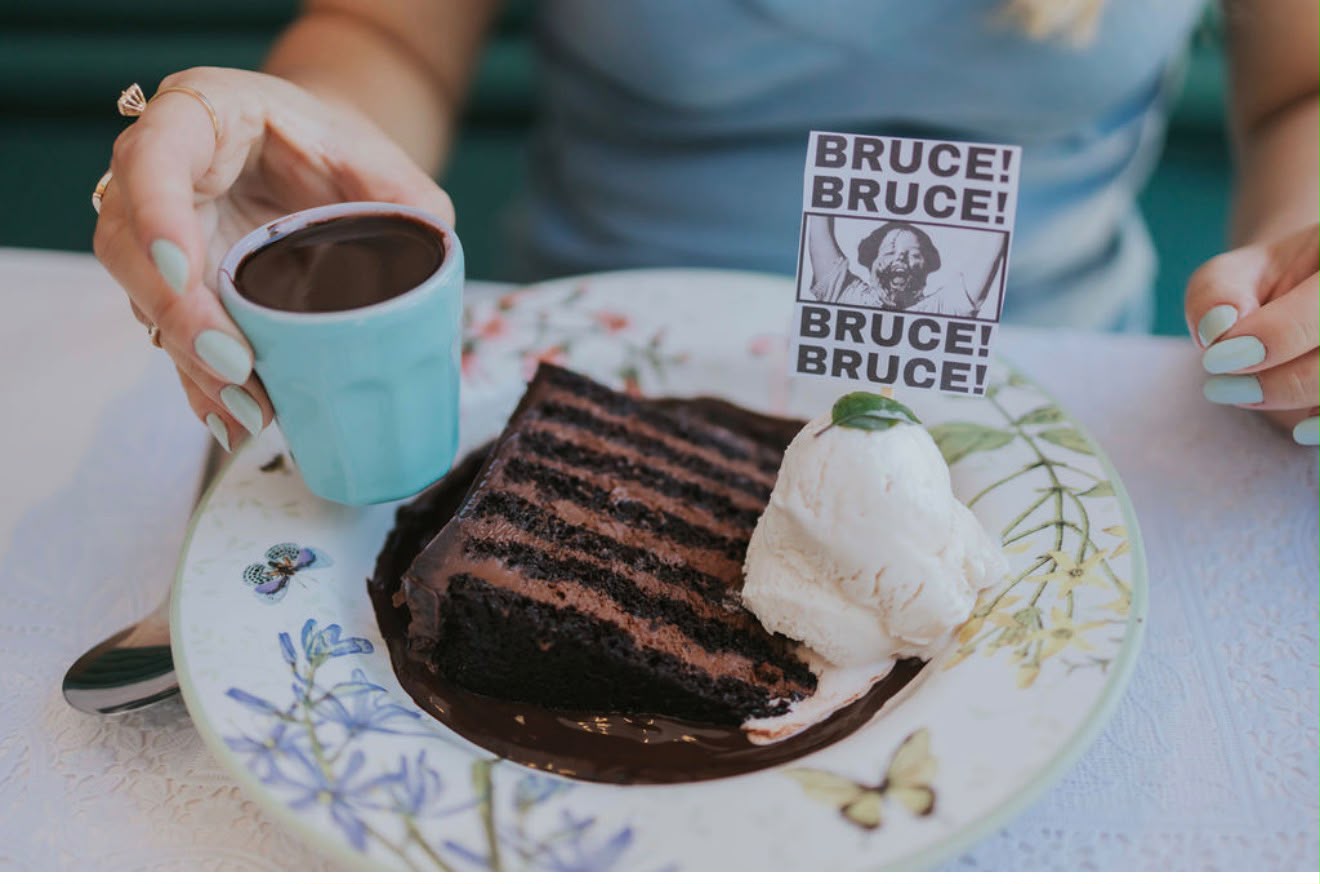 Fatia de bolo de chocolate com sorvete servida em prato floral, acompanhada de café